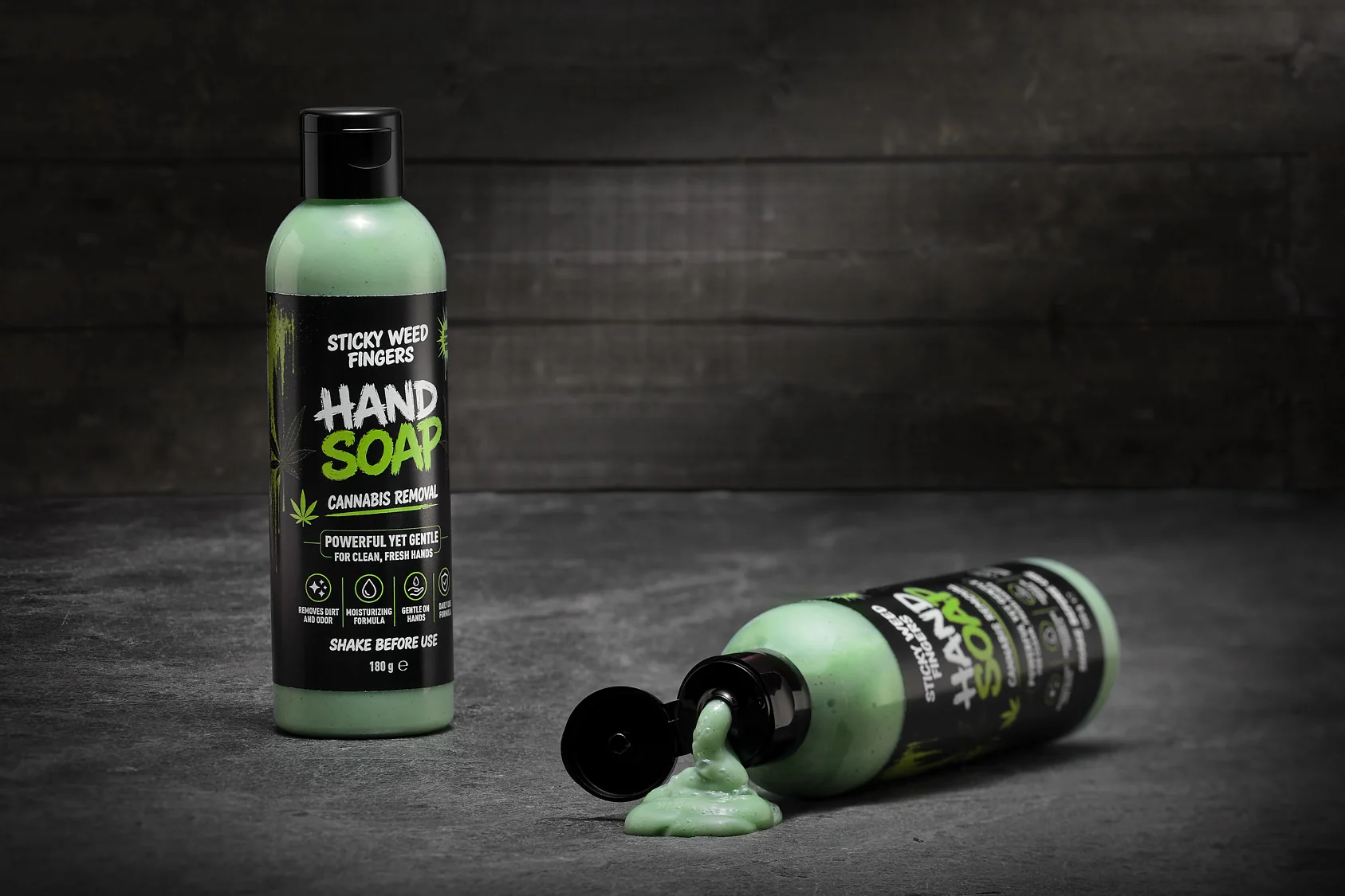 To flasker Sticky Weed Fingers Hand Soap på mørkt betonunderlag — den ene ligger og hælder sæbe ud